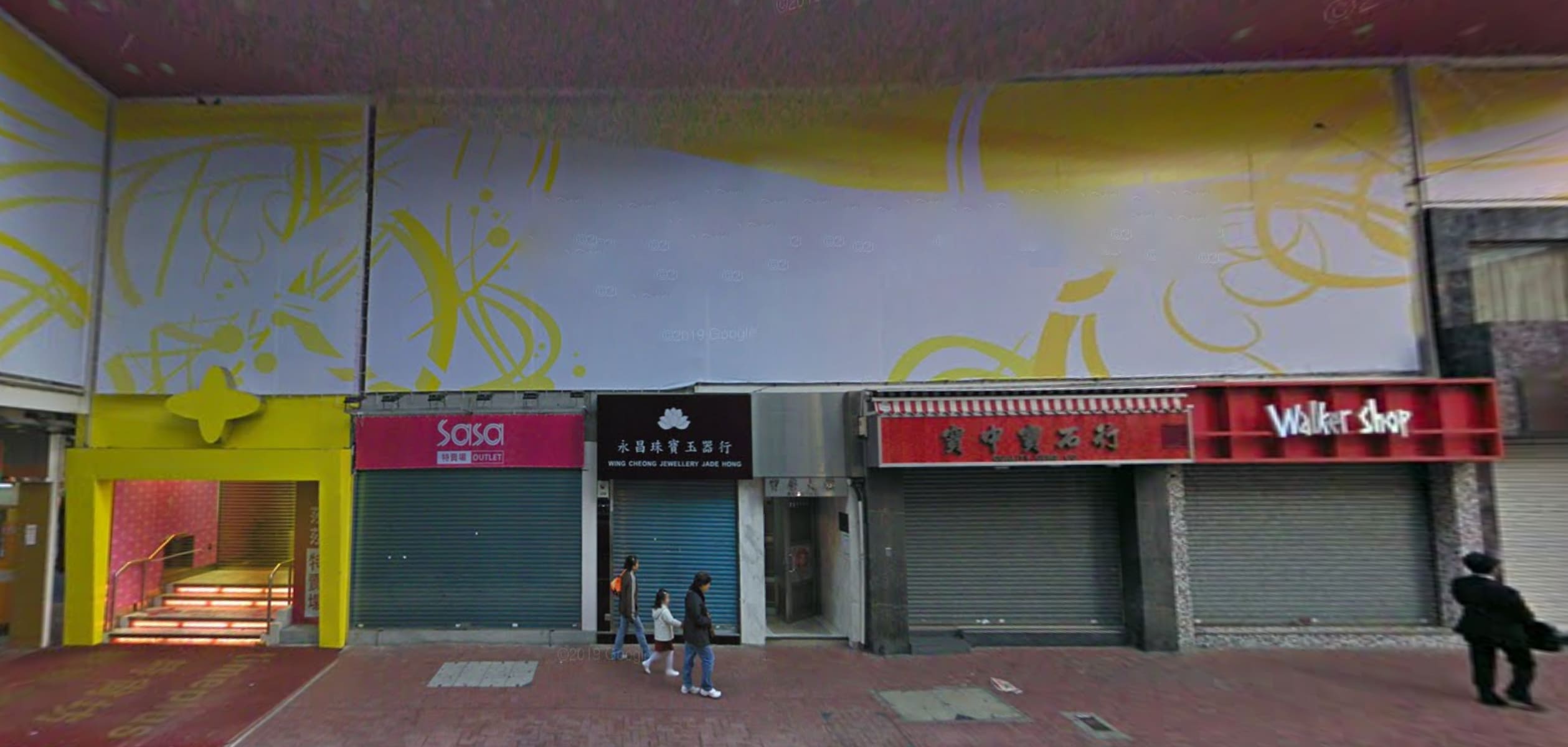 Street view of closed shops with colorful signs, including "Sasa" and "Walker Shop." Ref#3030 could be ideal if you're looking to rent shop space or a restaurant. A few people are seen walking along the sidewalk.