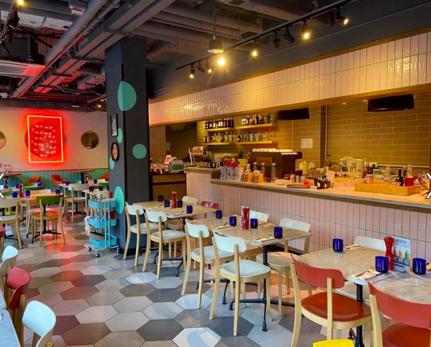 Ref#3028 is a modern café with hexagonal tile flooring, pastel chairs, a long counter, blue cups, and red pepper mills on tables beneath a glowing red neon sign—ideal for those seeking to rent a shop or restaurant.