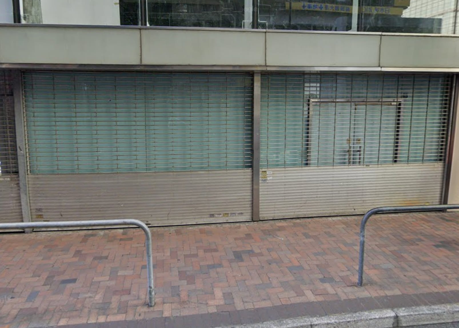 Ref#3016: Closed shop with metal shutters down over windows and door, fronting a brick-paved sidewalk with railingsperfect for rental as a shop or restaurant.