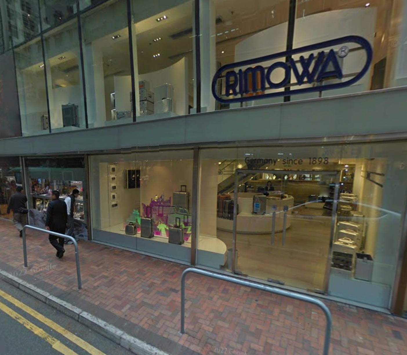 Street view of a Rimowa store with glass windows and a Rimowa sign above, next to rent shops and restaurants. Ref#3016 luggage is displayed inside, along with Germany since 1898..
