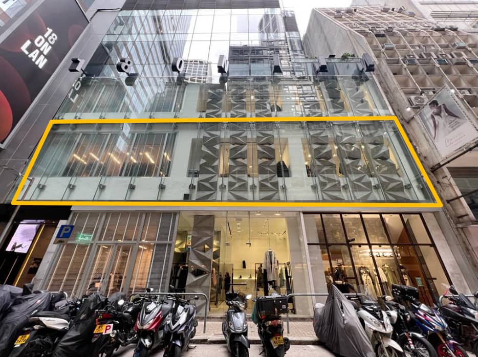 中環安蘭街餐廳舖位。一座玻璃幕牆建築物,二樓窗戶以黃色線條勾勒,前方停泊電單車。