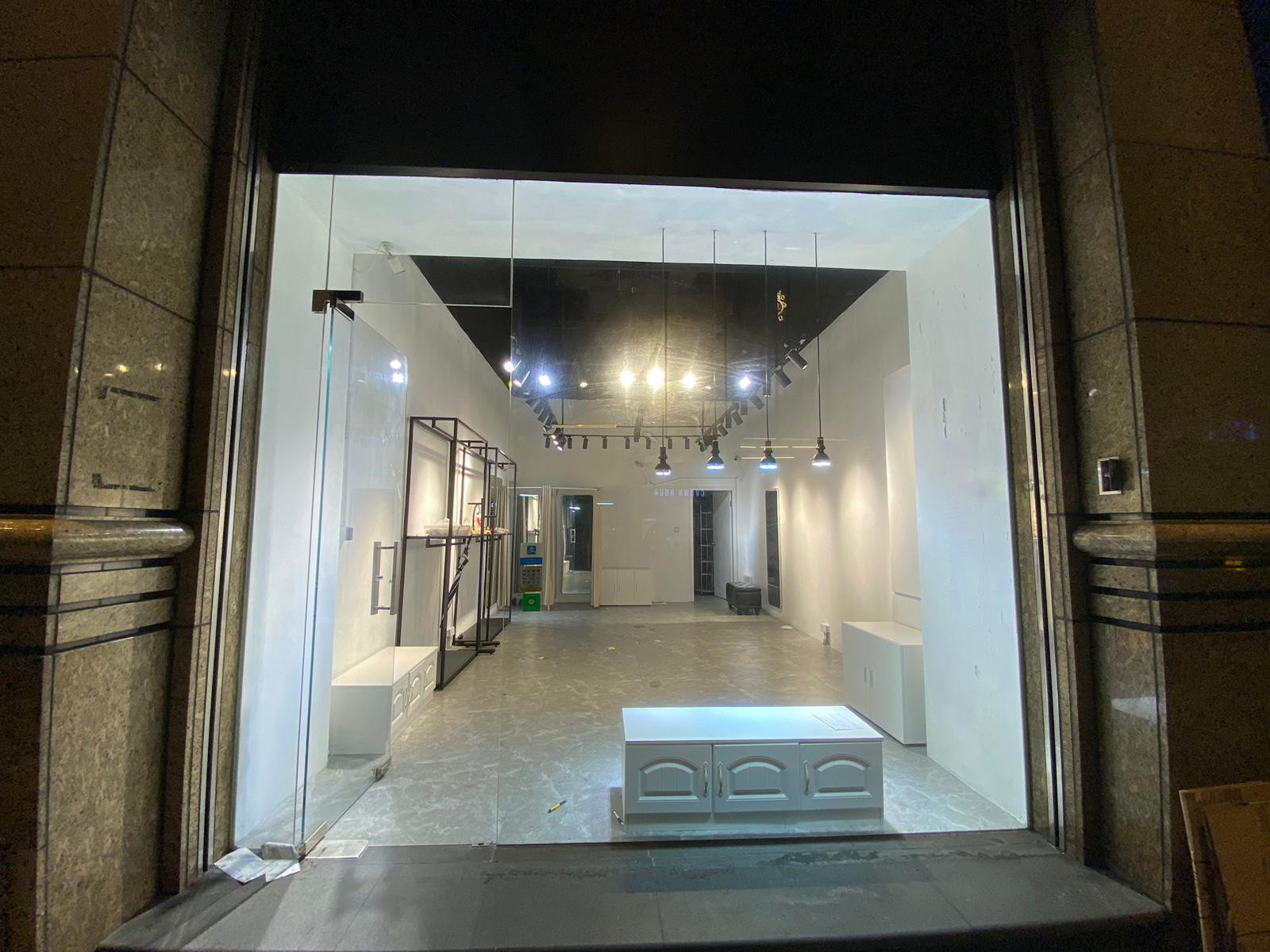 Ref#2982: A modern, empty retail store with white walls, shelves, and display units. Brightly lit and visible through a large glass entrance40ideal for shop rental.