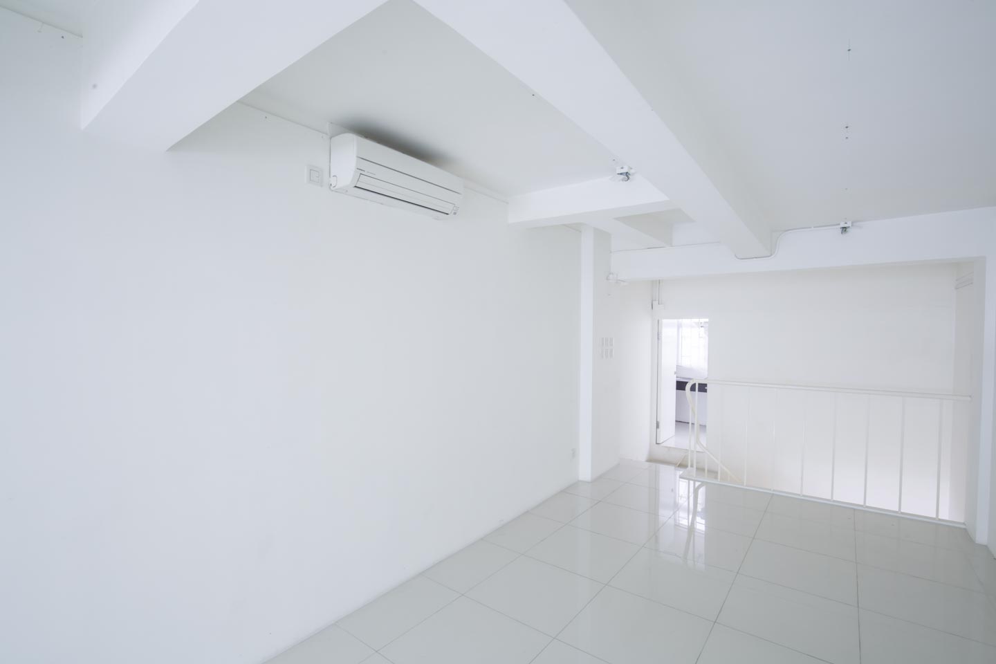 Empty white room on Hollywood Road in Central with tiled floor, exposed beams, air conditioner, and staircase with railing.