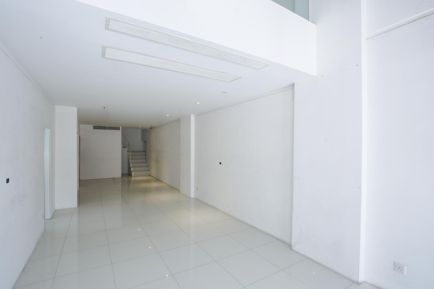Ref#2981 is a bright, modern space with white tiled floors, plain walls, and a rear staircase1 perfect for renting as a shop or leasing as a restaurant. Its clean lines and minimal decor offer versatile possibilities.