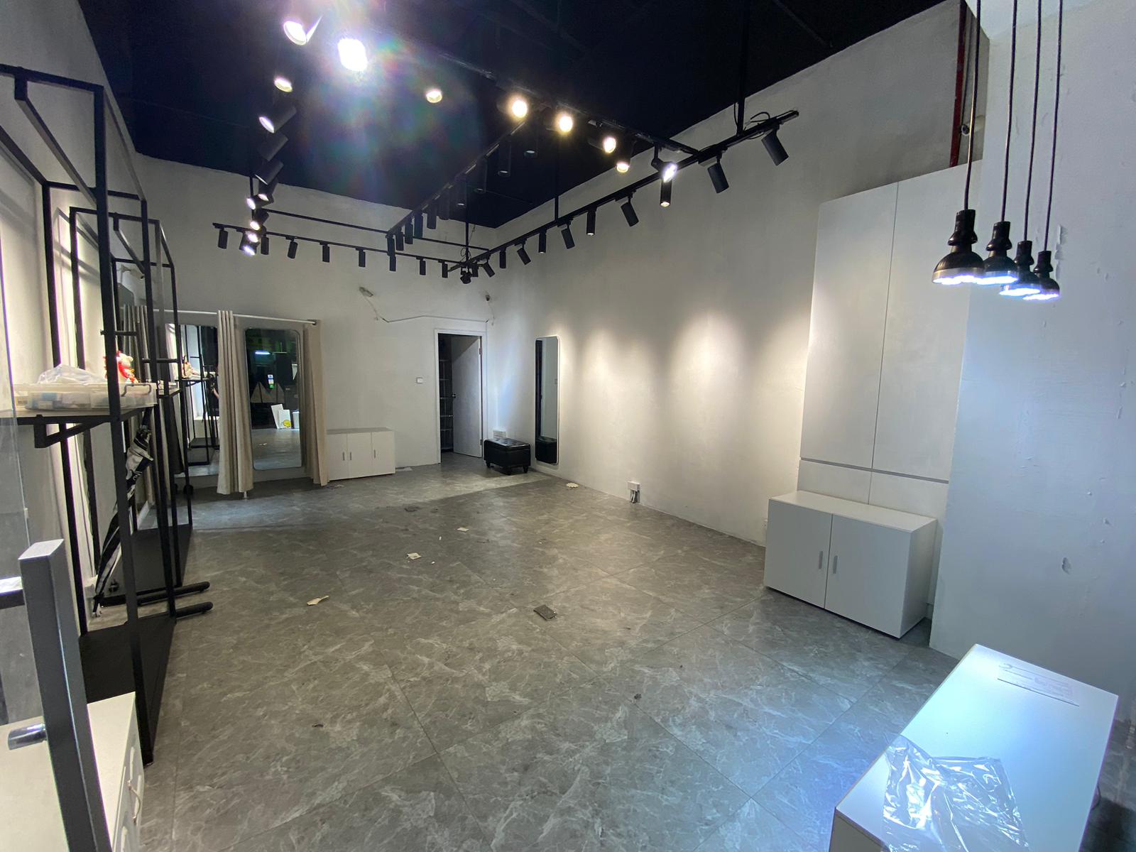 Ref#2982: A modern, unfurnished room with gray tile floors, white walls, ceiling track lighting, mirrors, and wall cabinets40ideal to rent as an office or shop and ready for your setup.