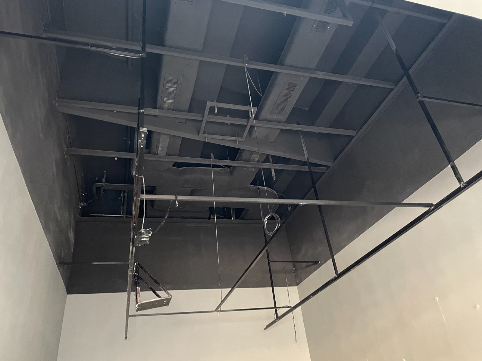 Ref#2982: Unfinished ceiling with exposed beams, ducts, cables, and metal framework in a room ready for rent40perfect for customizing as a restaurant, shop, or office. Bare walls and no ceiling tiles installed.