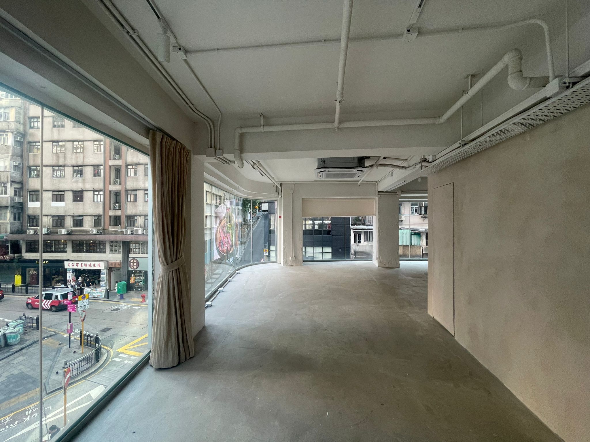 Ref#2980 is a modern, versatile space with floor-to-ceiling windows overlooking a busy street perfect to rent as an office or shop. Features include plain walls, exposed pipes, and concrete floors for a contemporary vibe.