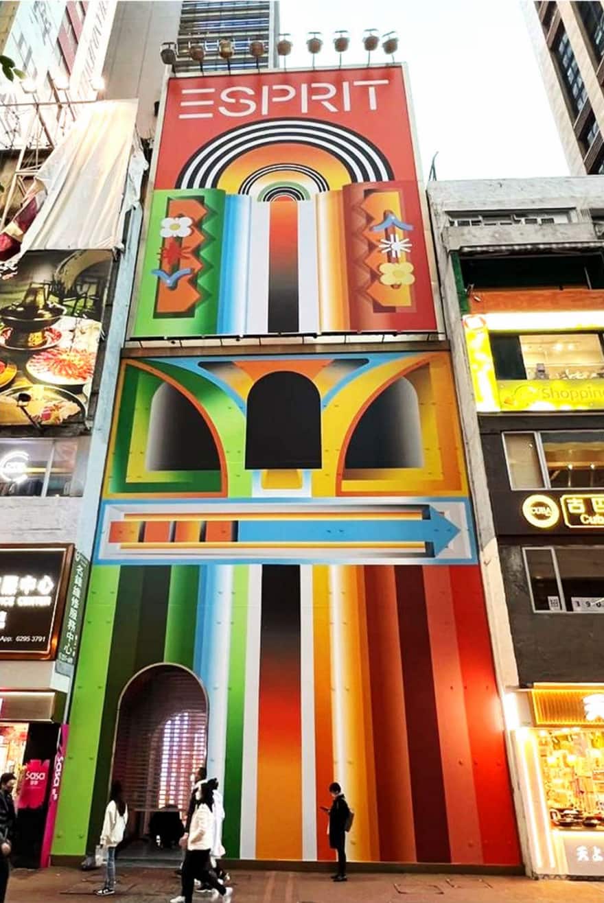 A tall building facade with bold rainbow geometric patterns and "ESPRIT" at the top. Several people walk past the entrance—Ref#3119, perfect for a vibrant shop or restaurant rental.
