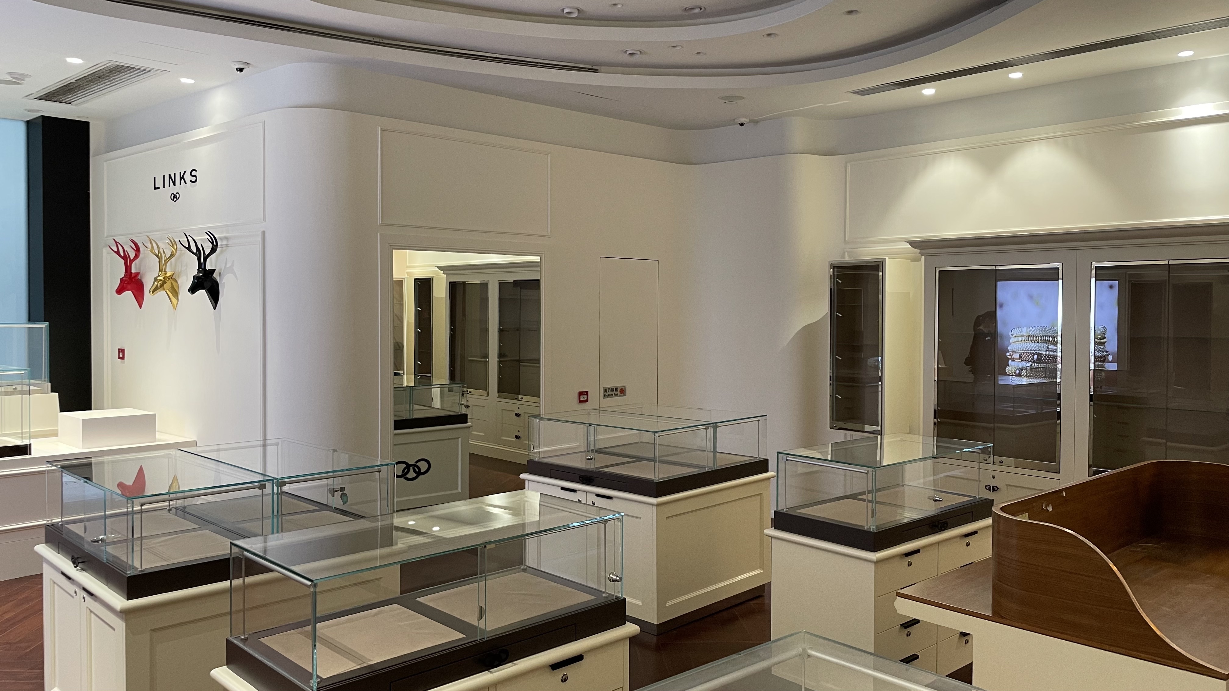 Ref#3046: A vacant jewelry or retail shop for rent featuring glass display cases, white walls, and colorful decorative deer heads. The store is clean, well-lit, and ready for use, with no products or customers present.