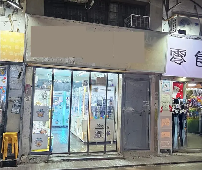 Shop on Wo Lung Street, Fanling. Glass-fronted shop with claw machines, next to other stores and a yellow plastic stool outside.