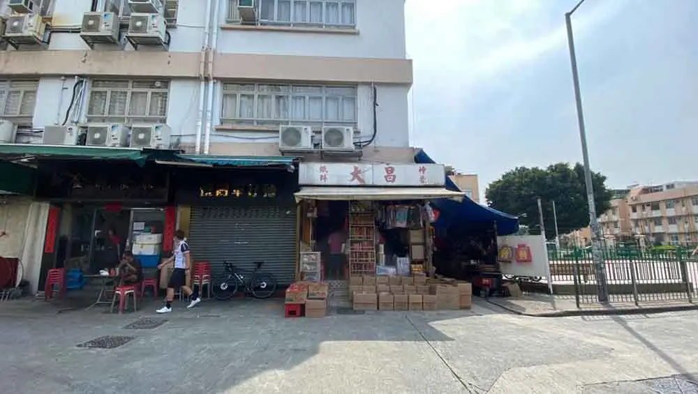 Shop on Hung Shui Kiu Main Street, Yuen Long. Hung Shui Kiu Main Street, Yuen Long with shops, stacked boxes, bicycles, chairs and air conditioners above storefronts.