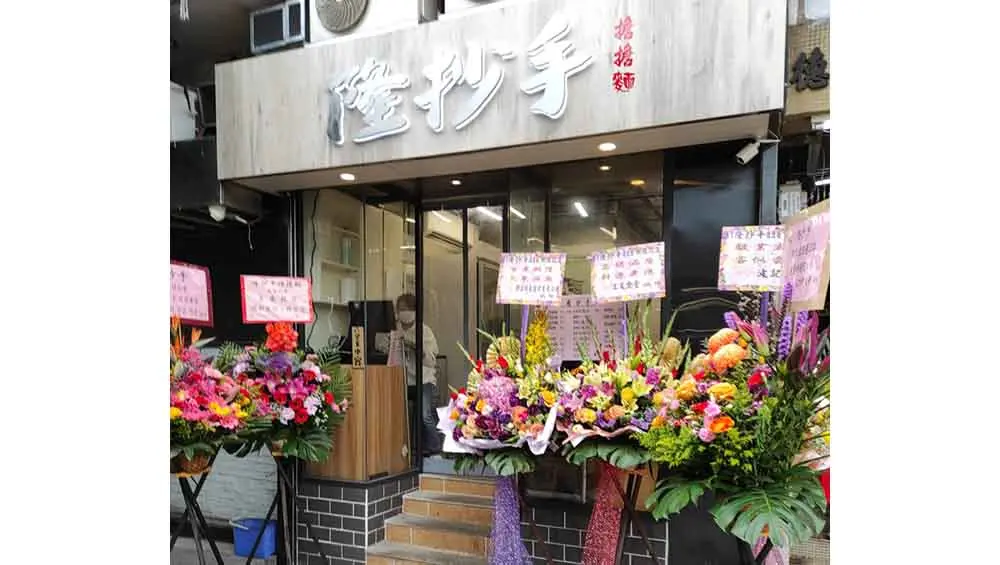 Restaurant space on Hung Shui Kiu Main Street, Yuen Long. Flower stands with congratulatory signs line a Yuen Long restaurant with Chinese signs above.