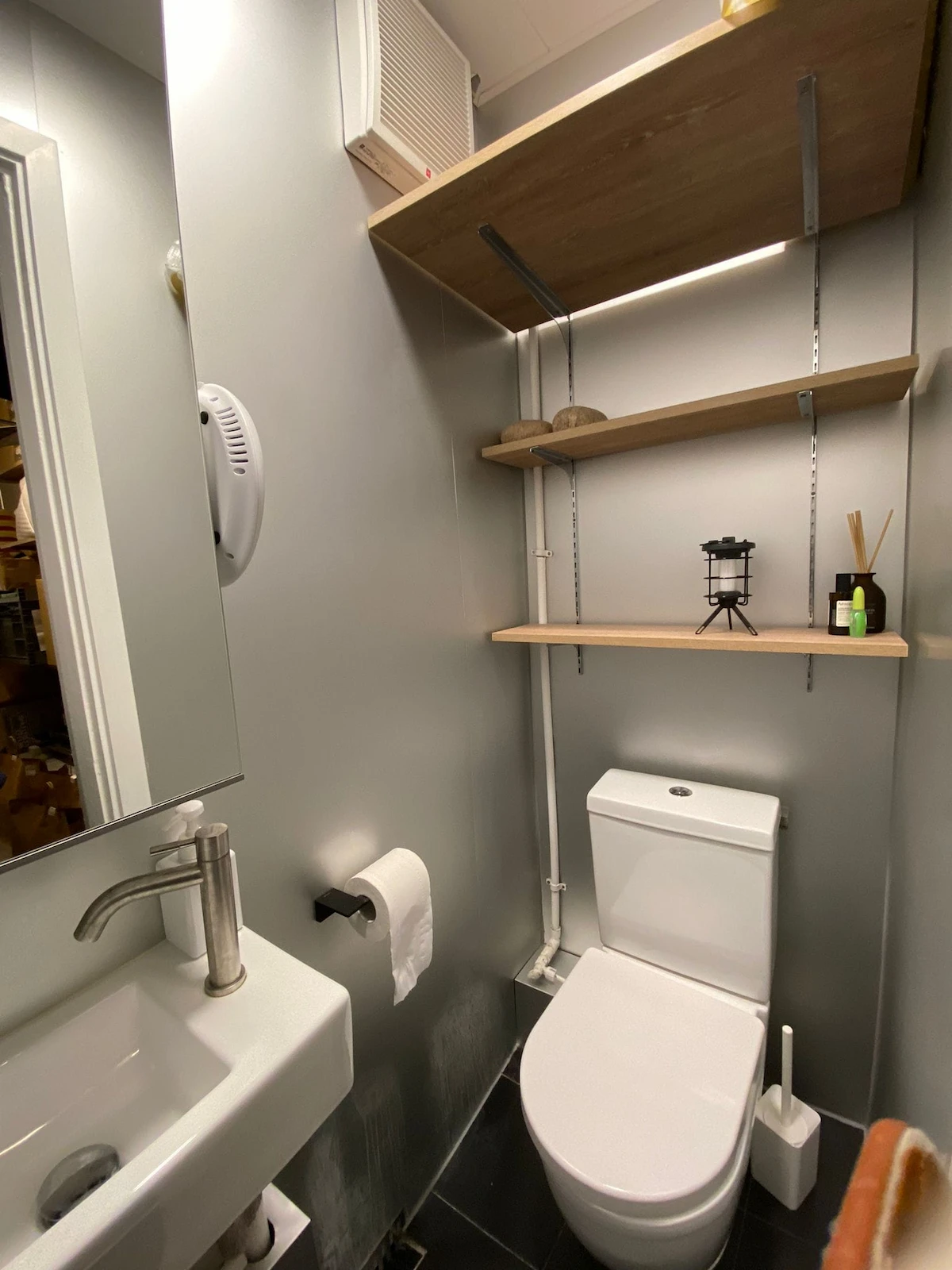 Small bathroom on Second Street Sai Ying Pun features a sink toilet shelving above and neatly organized items.