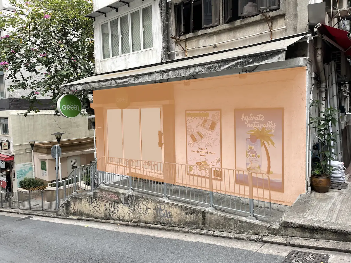 Peach-colored storefront on Graham Street, Central, featuring two posters, a ramp, railings, and a green sign.