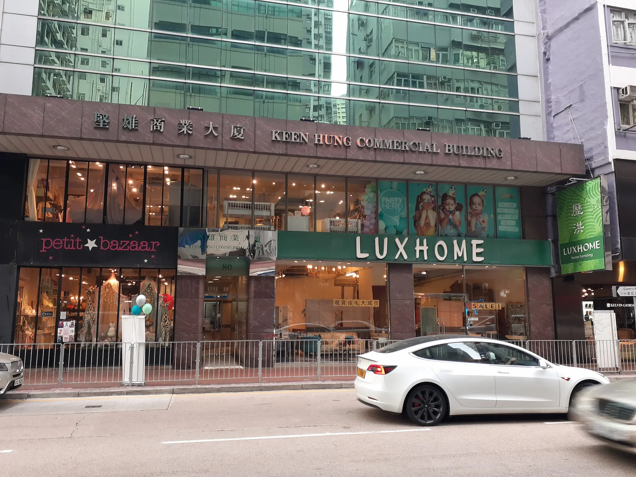 Shop on Queen's Road East, Wan Chai. Luxhome and Petit Bazaar storefronts on Queen’s Road East with cars driving past the building.