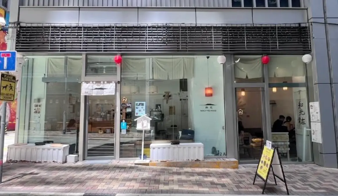 Shop on Chung Ching Street, Sai Ying Pun. Glass-fronted storefront, white decor, bench outside, signage and red lanterns above.