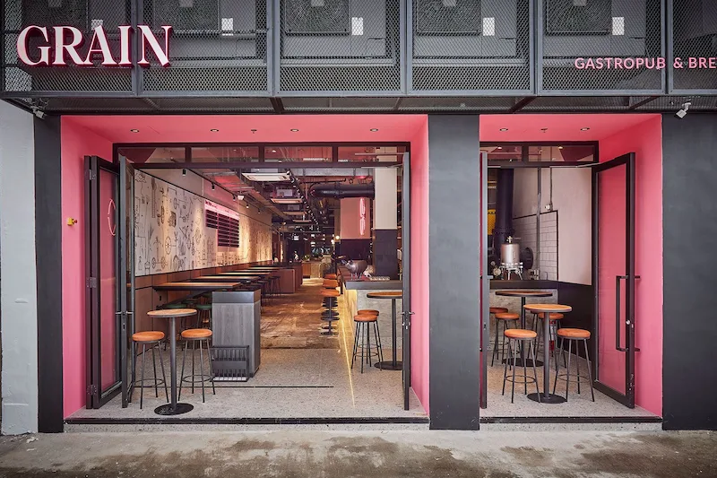 Restaurant space on New Praya, Kennedy Town. Street view of GRAIN gastropub in Kennedy Town with pink trim, open doors, and indoor seating visible.