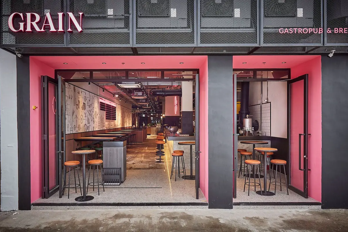 Modern gastropub exterior with pink accents on New Praya, Kennedy Town; bar stools and tables seen inside.