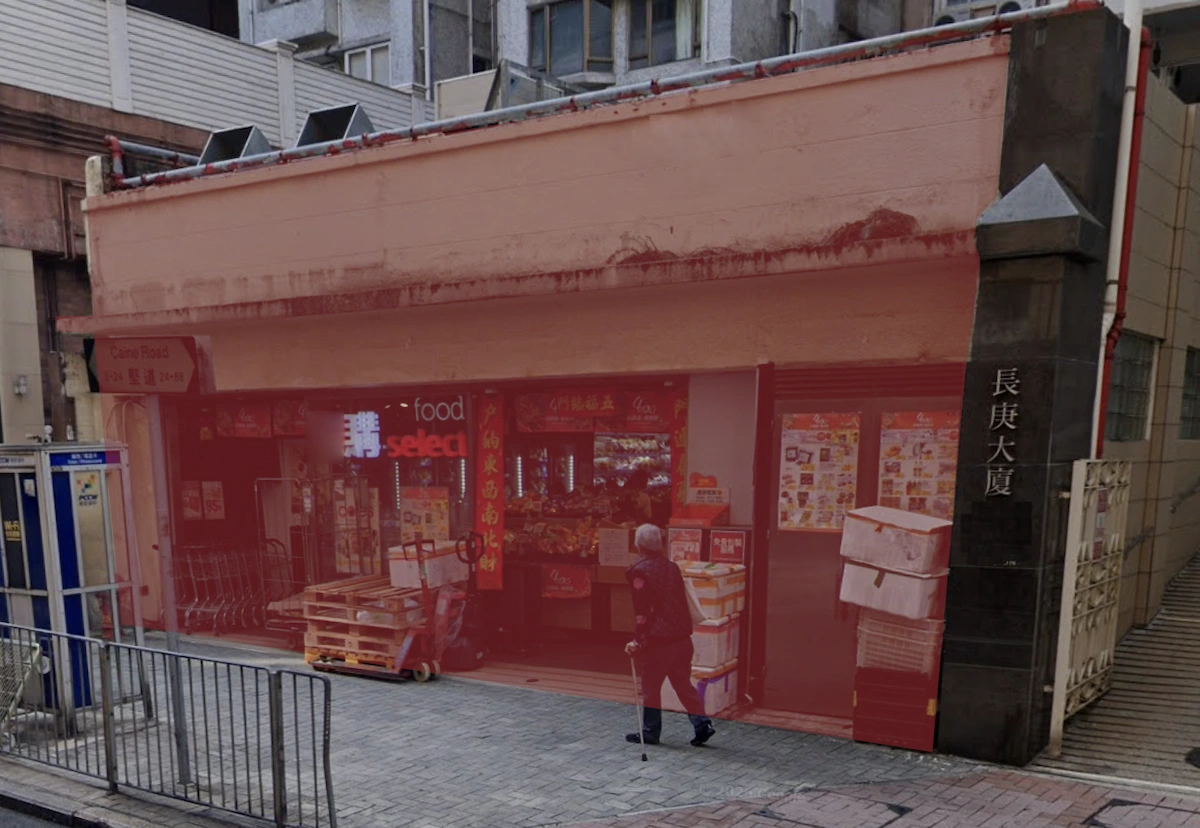 A person walks past a small storefront on Caine Road in Mid-Levels with boxes and carts stacked outside.