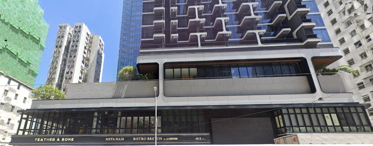 德輔道西一幢多層大廈設幾何形陽台及地下舖位，背景為西營盤天際線。