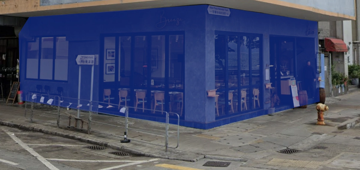 Corner cafe on New Praya, Kennedy Town with blue walls, large windows, and empty tables visible inside.