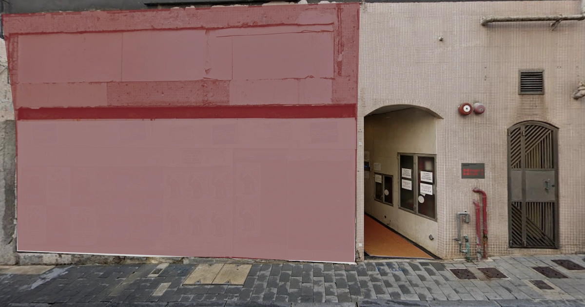 A beige building with a red facade on Elgin Street has an open doorway revealing a tiled interior hallway.