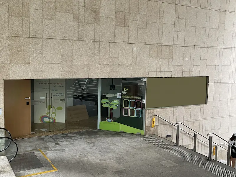 西營盤舖位。第一街一幢米色石材建築設彩色貼紙玻璃門，旁為樓梯及扶手電梯。