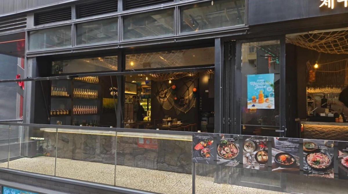 Modern restaurant on Cochrane Street Central with glass windows outdoor tables and food posters visible.
