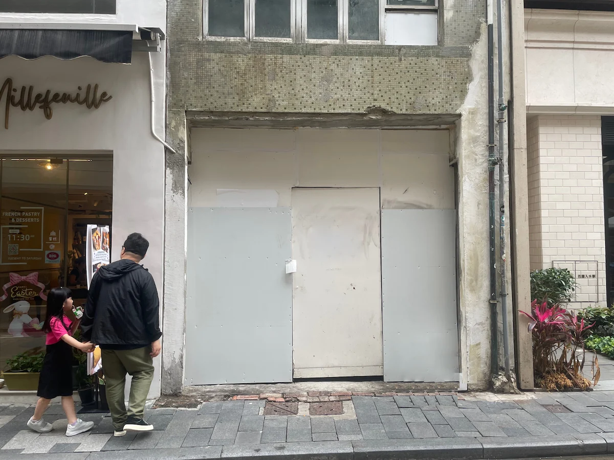 A man and a girl walk past a shuttered storefront on Staunton Street in Central, Hong Kong.