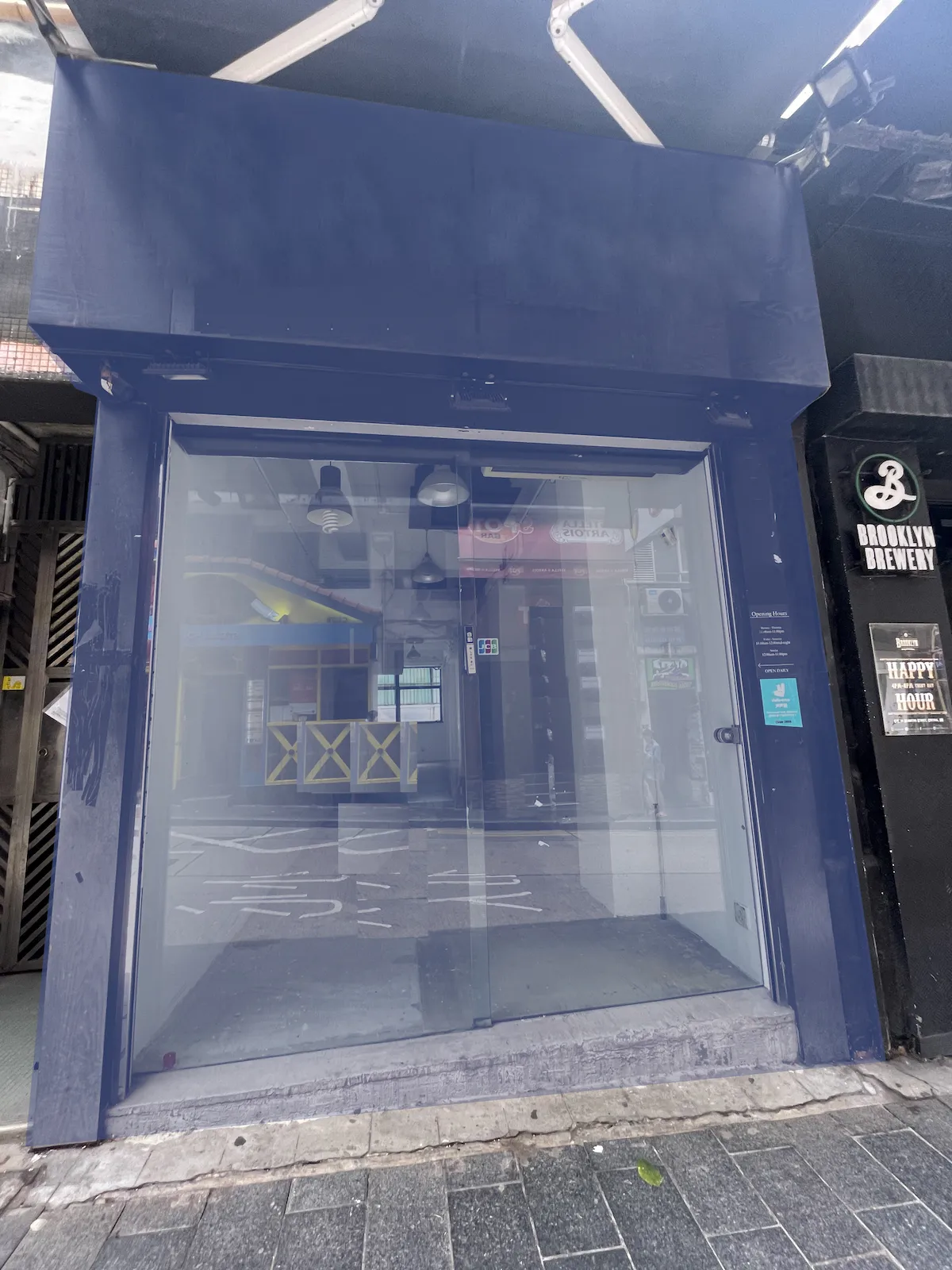 Vacant storefront with blue frame on Staunton Street, Central, glass door reflects surrounding buildings and street.