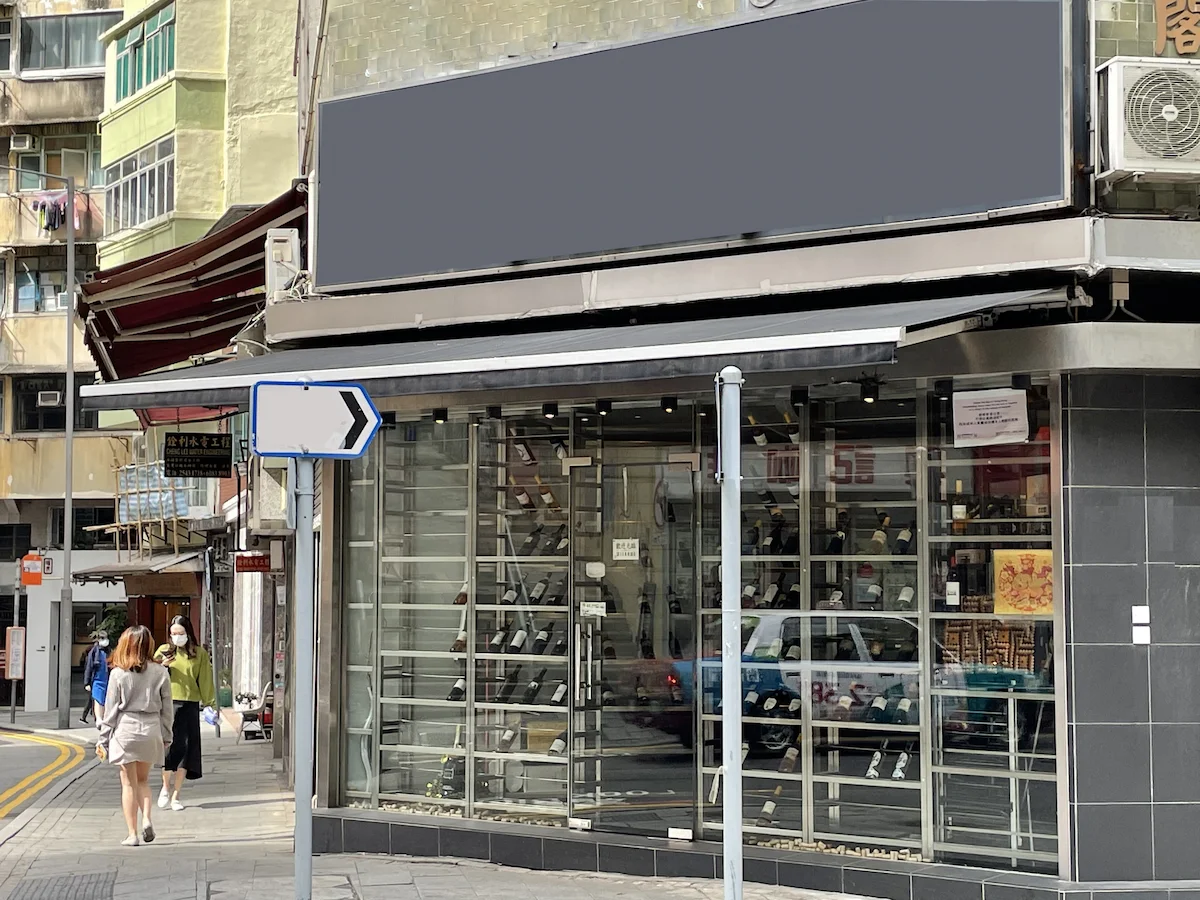 Storefront with blank signboard, glass windows, and a right-turn sign on Hollywood Road in Sheung Wan urban area.