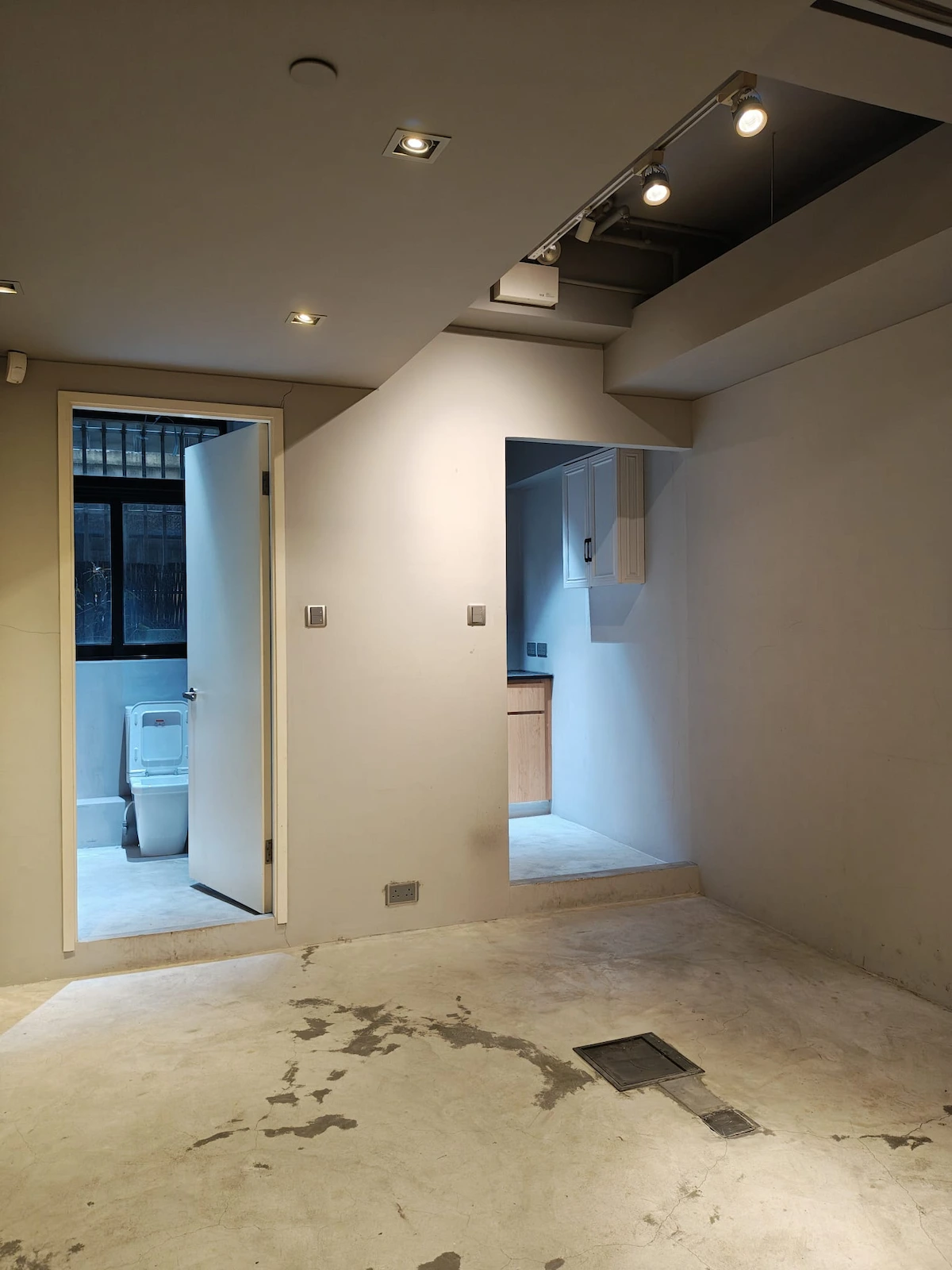 Empty room on Hollywood Road, Sheung Wan, showing open door to toilet and view into a compact kitchen area.