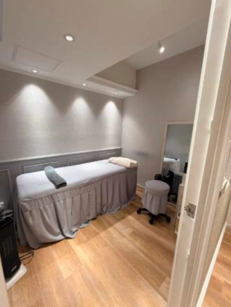 Shop on Lan Kwai Fong, Central. Minimalist massage room near Lan Kwai Fong with soft lighting, wooden floors, table, stool and mirror.
