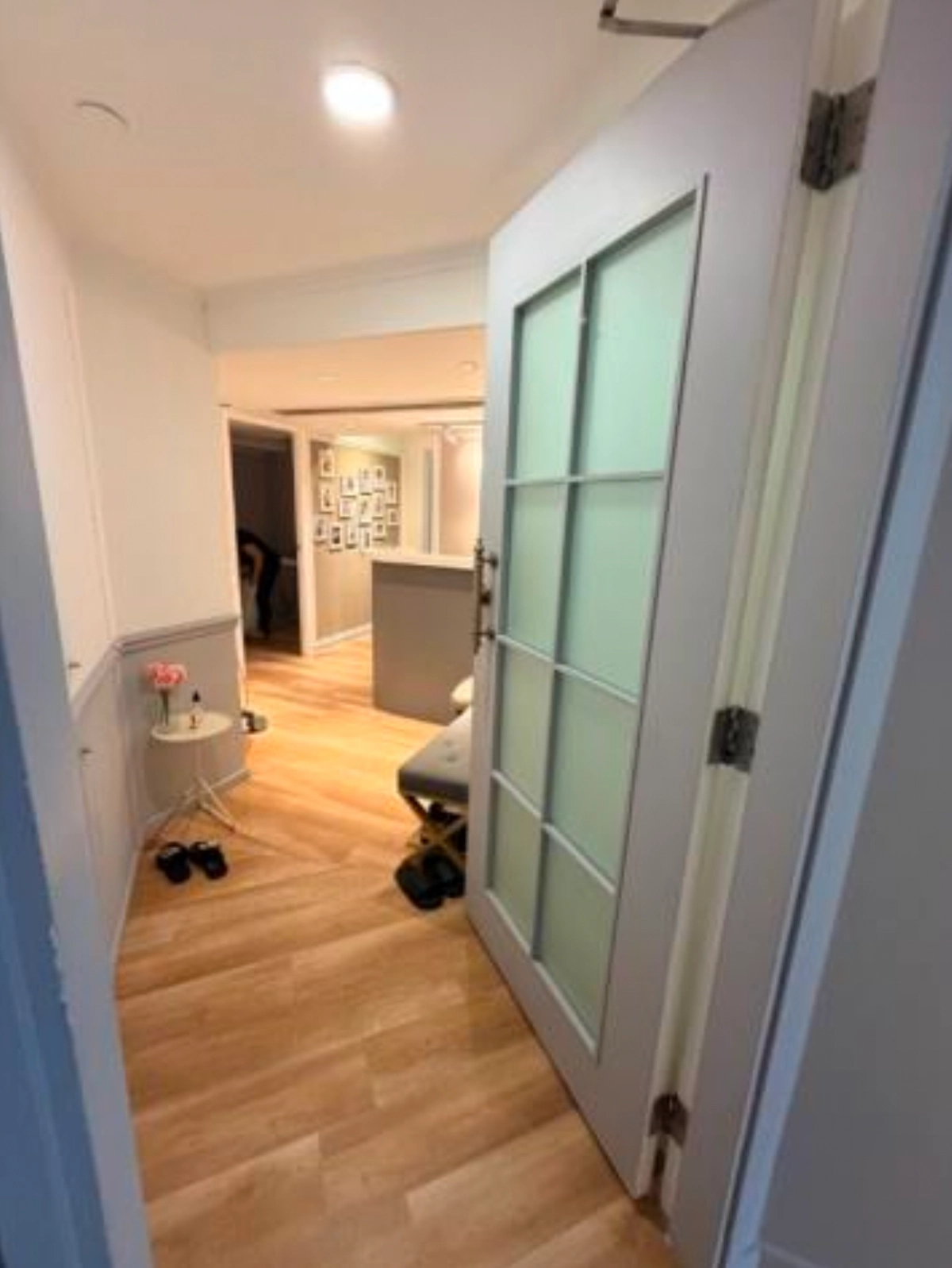 An open frosted glass door in Central reveals wood floors, a side table, and Lan Kwai Fong-inspired art on the wall.