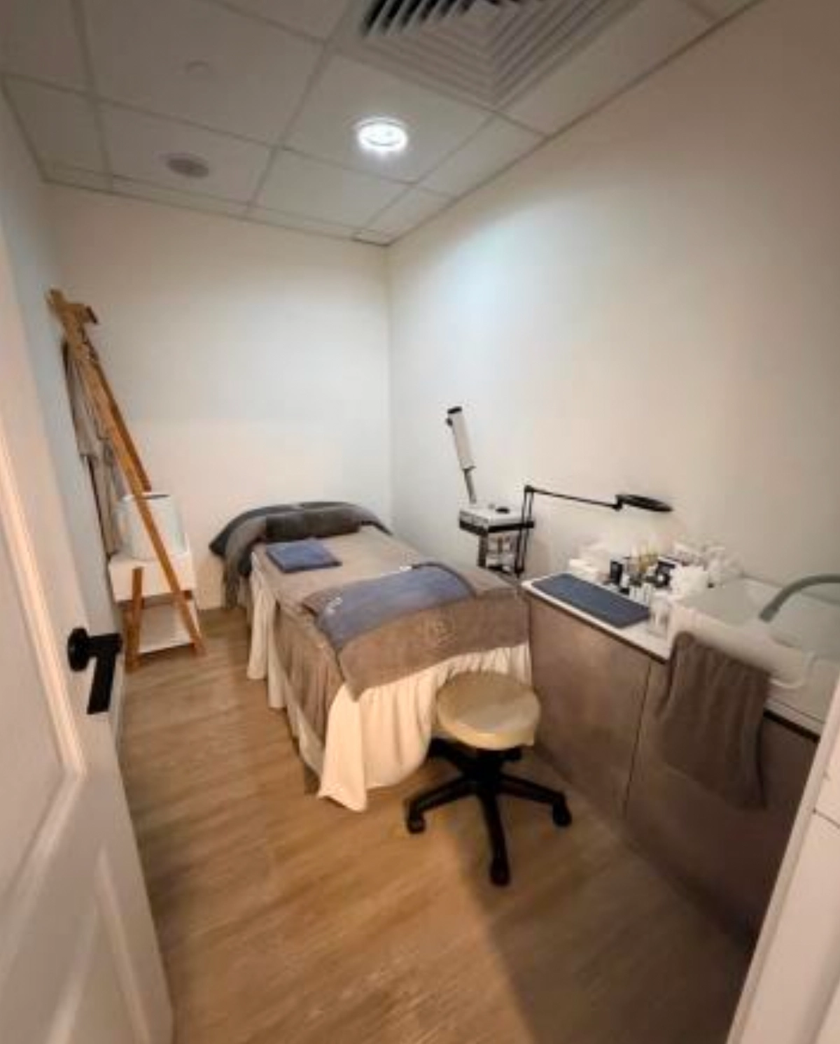 Treatment room on D’Aguilar Street, Central, with a massage table, rolling stool, and a wooden ladder shelf.