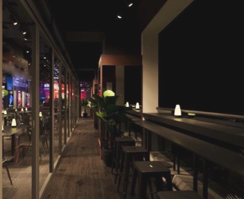 Restaurant space on D'Aguilar Street, Central. Indoor restaurant on D’Aguilar Street Central with wooden floors bar seating potted plants and dim night lighting.