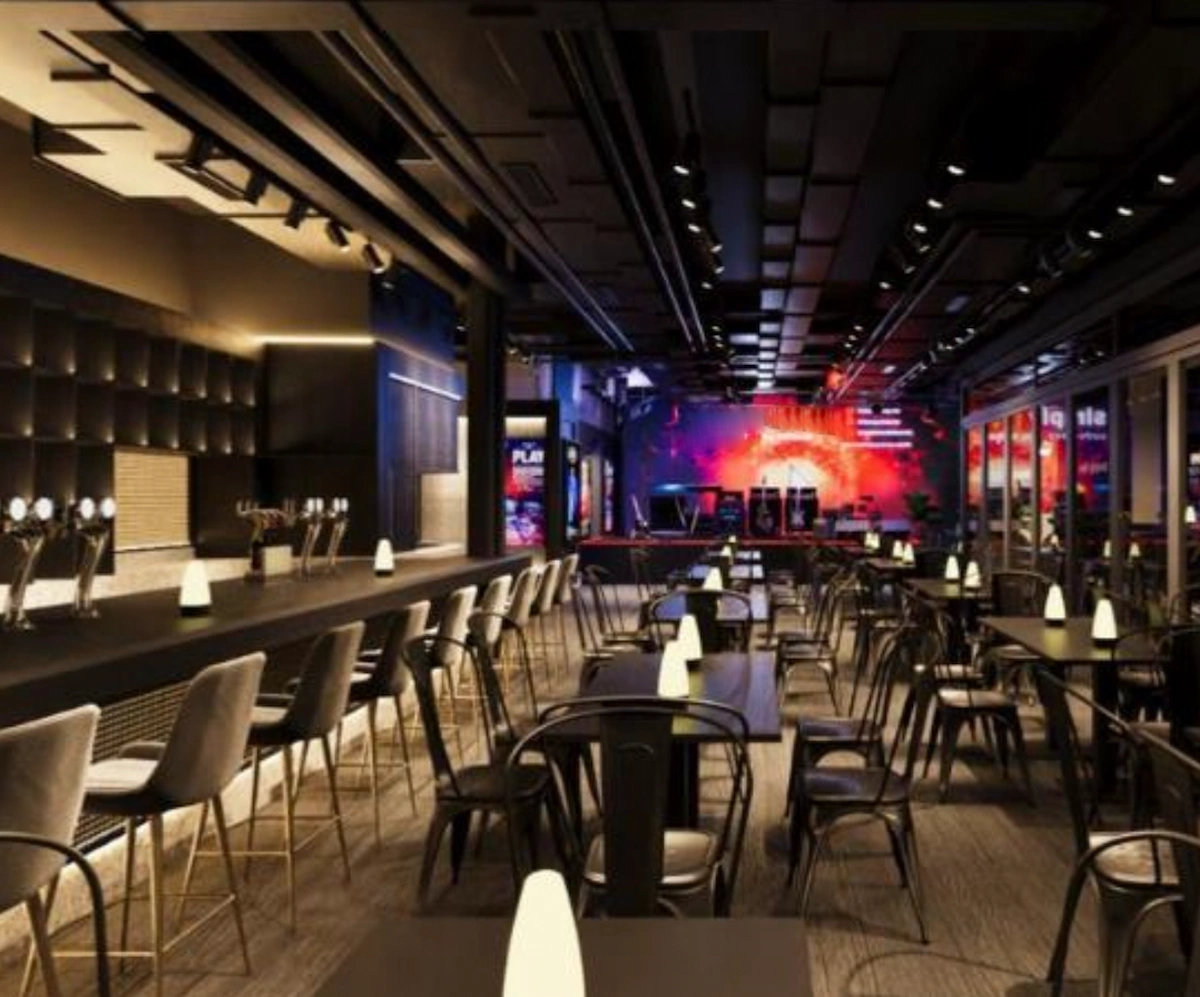 Bar on D’Aguilar Street with high-top stools, black tables, ambient lighting, and a digital screen.