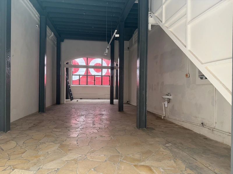 Shop on Wellington Street, Central. Empty room with stone tile floor, exposed beams, and a patterned window in the background.
