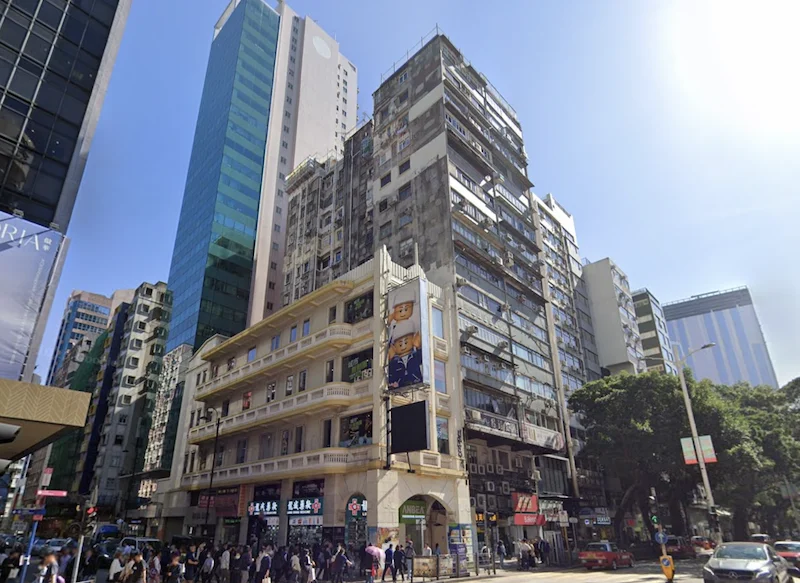 Shop on Nathan Road, Tsim Sha Tsui. Tall modern and older buildings line busy Nathan Road on a sunny day.