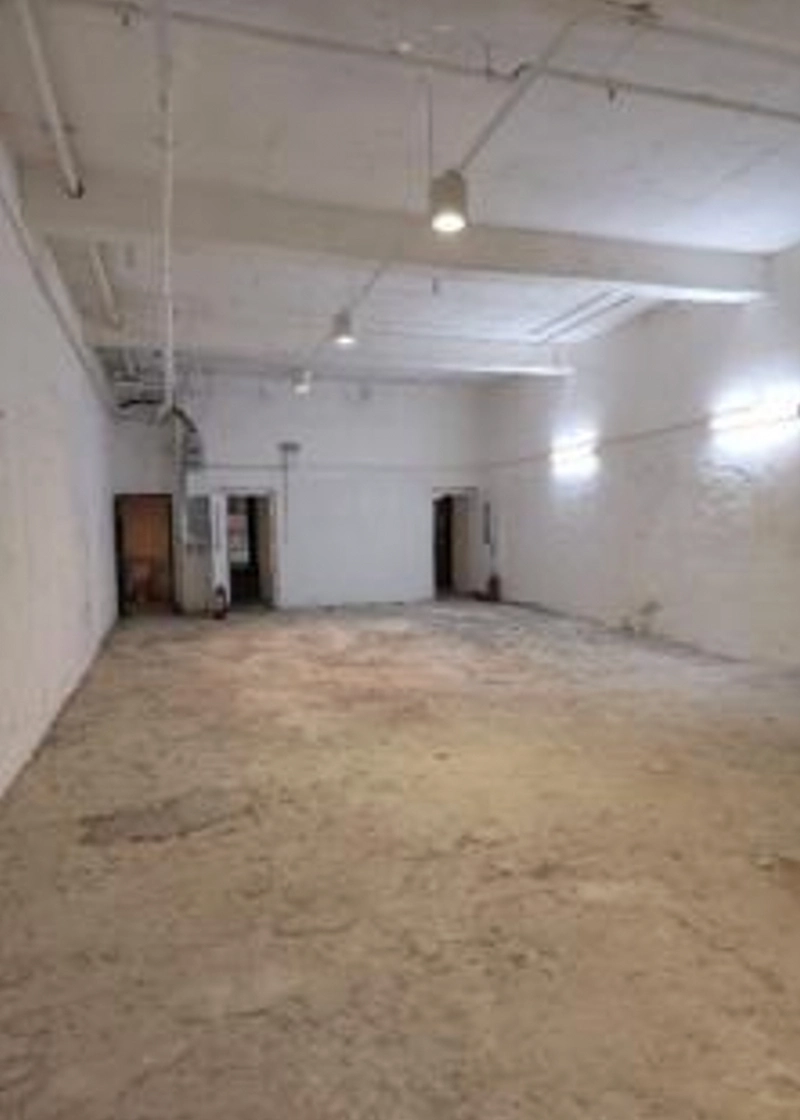 Shop on Nathan Road, Tsim Sha Tsui. Empty industrial space with white walls, concrete floor, overhead lighting, and open doorways.