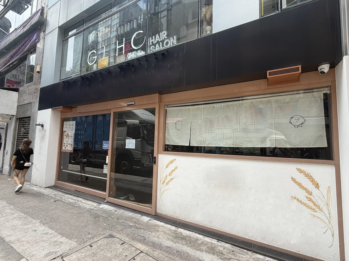 Granville Road, Tsim Sha Tsui: closed hair salon with wheat patterns on windows, woman walking past covered storefront.