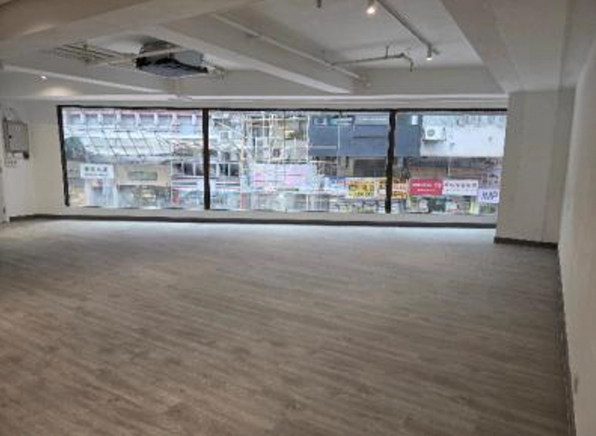 Empty room with large windows facing Queen’s Road Central in Sheung Wan, light gray flooring, and white walls.