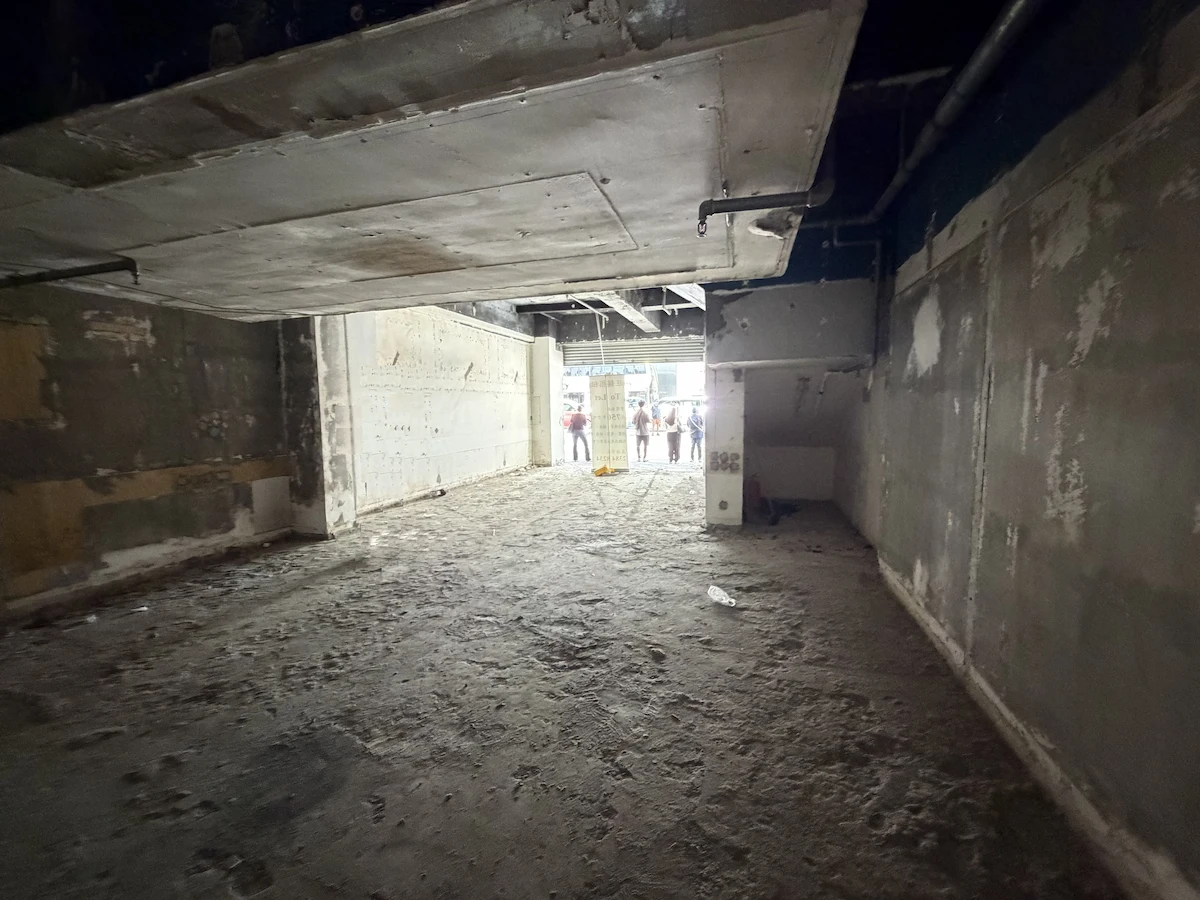 Unfinished concrete room with exposed pipes near Fleming Road in Wan Chai, people standing by the entrance.