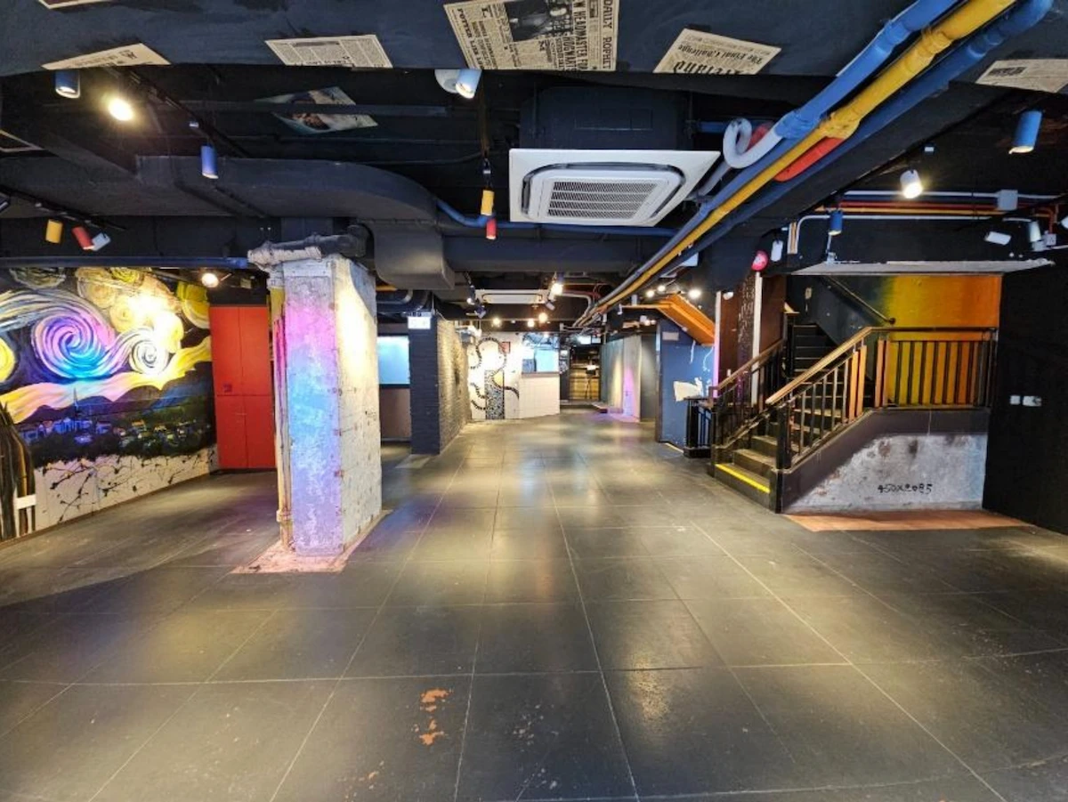 Modern basement near Granville Road with art murals, exposed pipes, columns, and a staircase to the upper floor.