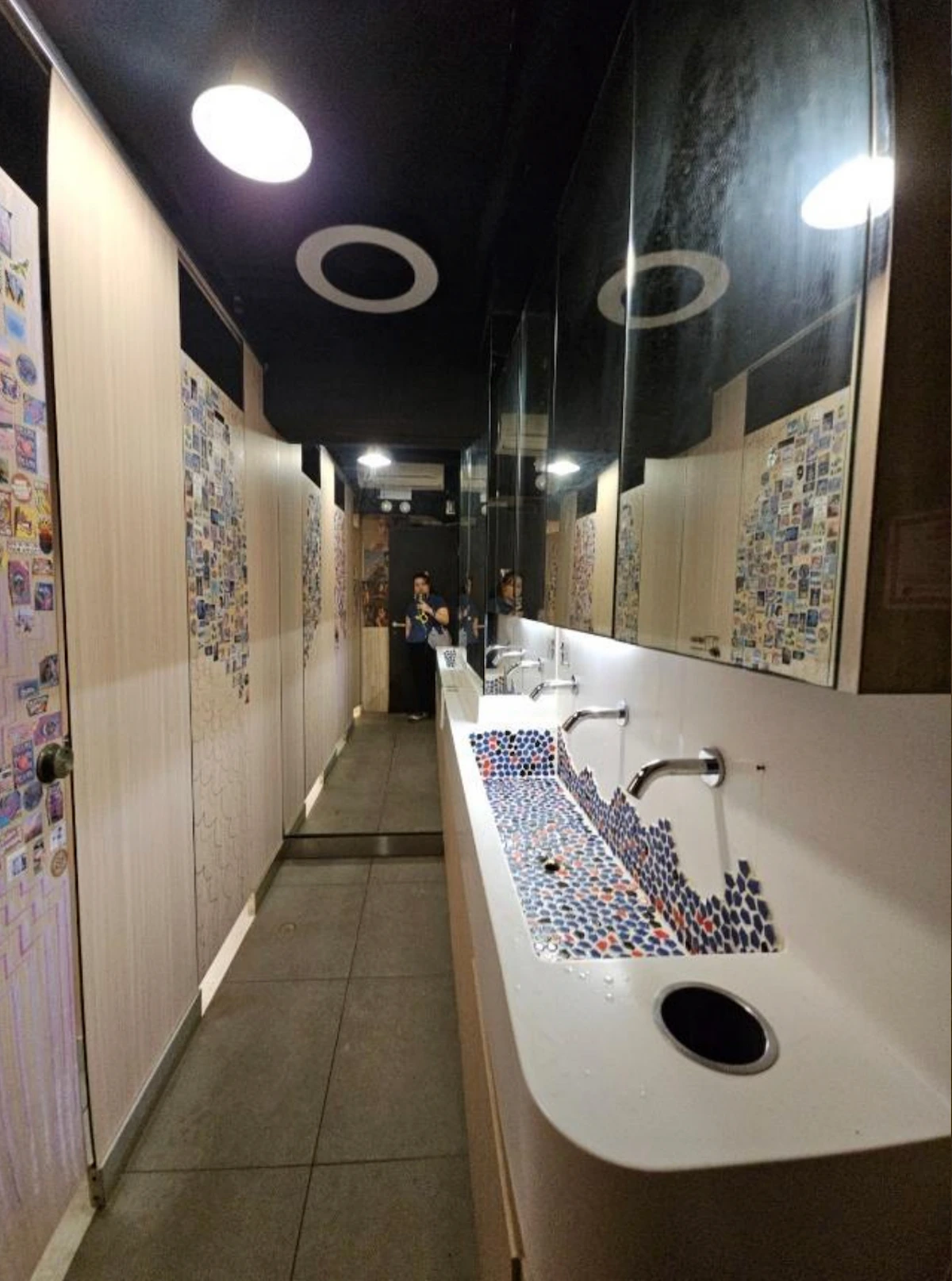 Public restroom on Granville Road featuring patterned sinks, stalls to the left, mirrors above, and ceiling lights.