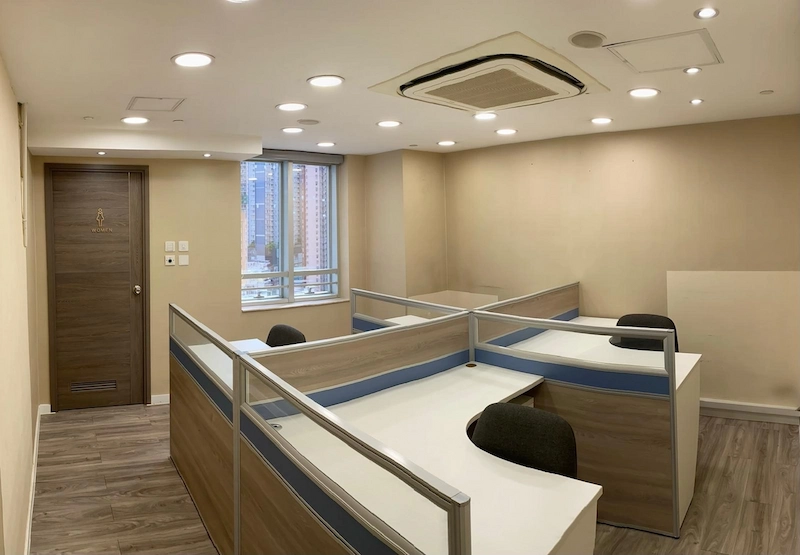 Office on Queen's Road Central, Central. Office with four empty partitioned workstations, wood floors, large window, and overhead lighting.