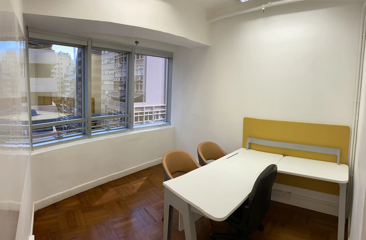Office room with three chairs, two desks, and large windows overlooking Queen’s Road Central and surrounding buildings.