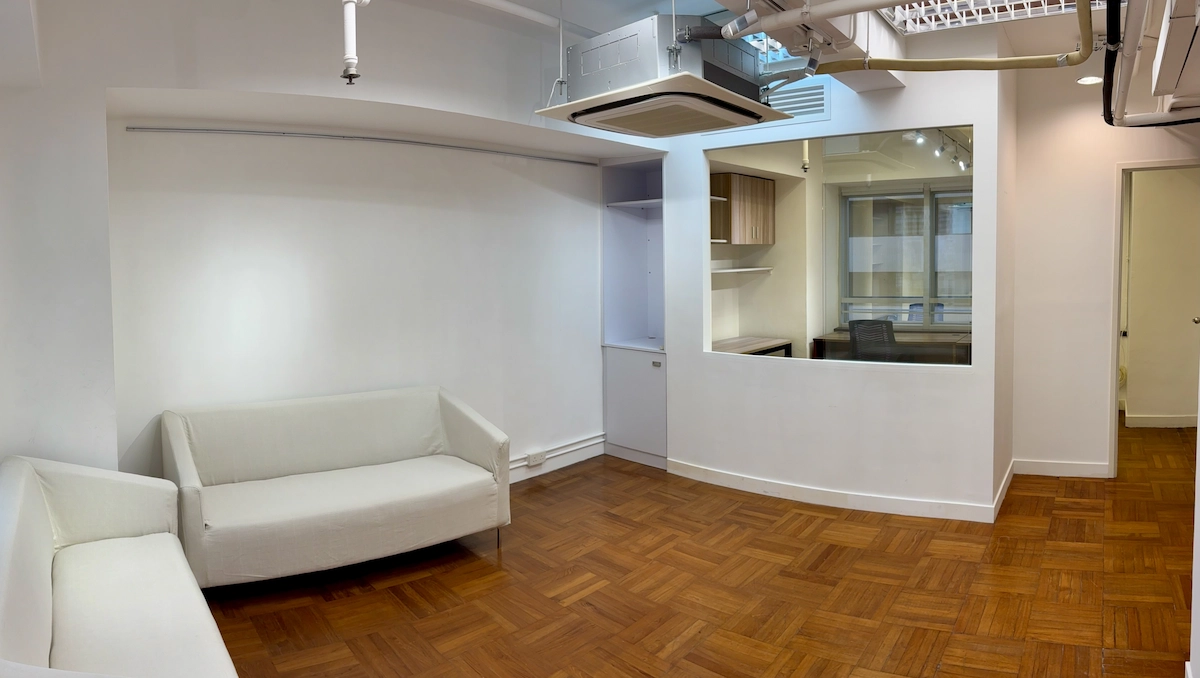 Office in Central with white sofas, wood flooring, large glass window, and exposed ceiling fixtures.