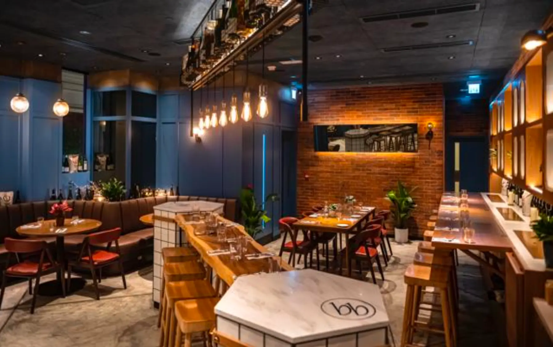 Restaurant with wooden tables, bar stools, and blue-brick walls near Lee Tung Avenue in Wan Chai.