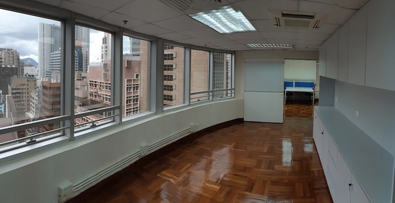Office on Queen's Road Central, Central. Empty office on Queen’s Road Central with wood flooring, city views, white cabinets, and bright ceiling lights.